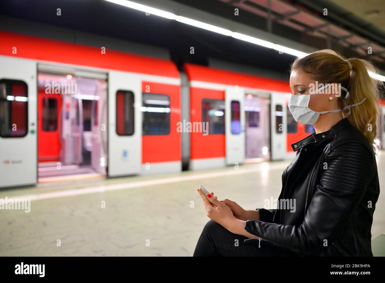 Woman with face mask, on mobile phone, waiting for train, S-Bahn, station Stadtmitte, Corona crisis, Stuttgart, Baden-Wuerttemberg, Germany Stock Photo