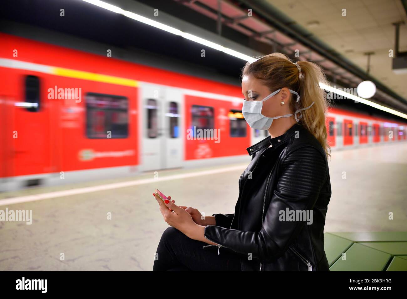 Woman with face mask, on mobile phone, waiting for train, S-Bahn, station Stadtmitte, Corona crisis, Stuttgart, Baden-Wuerttemberg, Germany Stock Photo