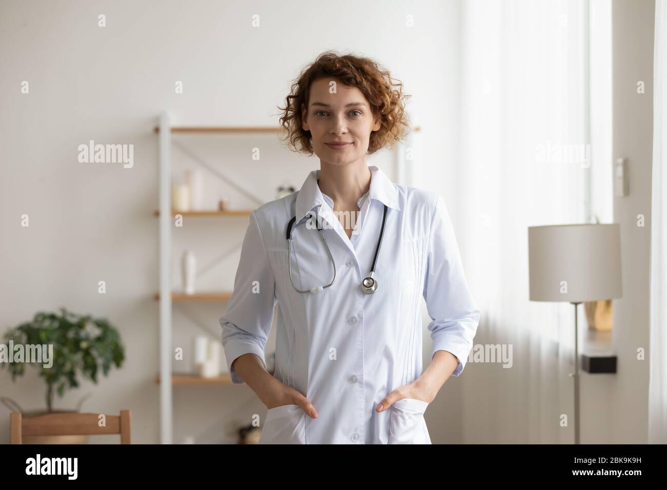 Confident young female physician standing in medical office interior, portrait Stock Photo