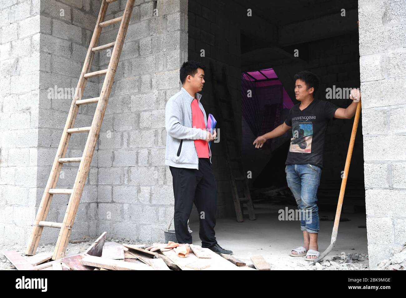 (200503) -- NANNING, May 3, 2020 (Xinhua) -- Yu Yang (L), a 32-year-old village official of Houlong Village, talks with a villager in Sicheng Township of Lingyun County, south China's Guangxi Zhuang Autonomous Region, April 17, 2020. In Guangxi, many young people are entrusted with the task of strengthening the Communist Party of China (CPC) at the grassroots level and aiding in poverty alleviation. They are working on the poverty relief front: going door to door to find about people's livelihood and coming up with ideas to help them shake off poverty. The youth of today shine in the cour Stock Photo