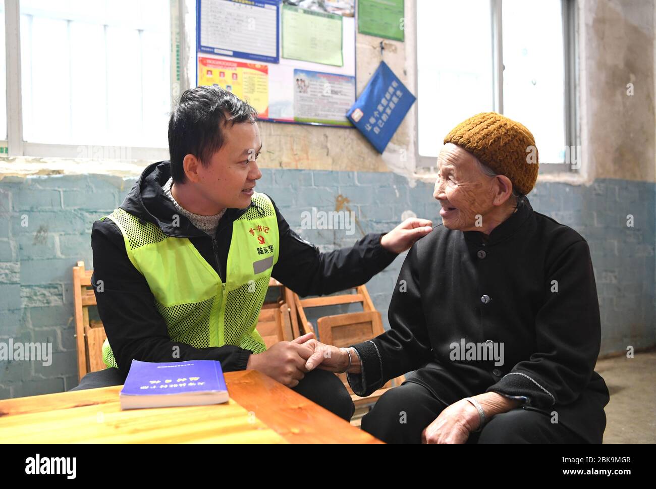 (200503) -- NANNING, May 3, 2020 (Xinhua) -- Lu Rongfei (L), a 32-year-old village official of Langming Village, talks with an elderly villager in Tiandeng County, south China's Guangxi Zhuang Autonomous Region, April 22, 2020. In Guangxi, many young people are entrusted with the task of strengthening the Communist Party of China (CPC) at the grassroots level and aiding in poverty alleviation. They are working on the poverty relief front: going door to door to find about people's livelihood and coming up with ideas to help them shake off poverty. The youth of today shine in the course of Stock Photo