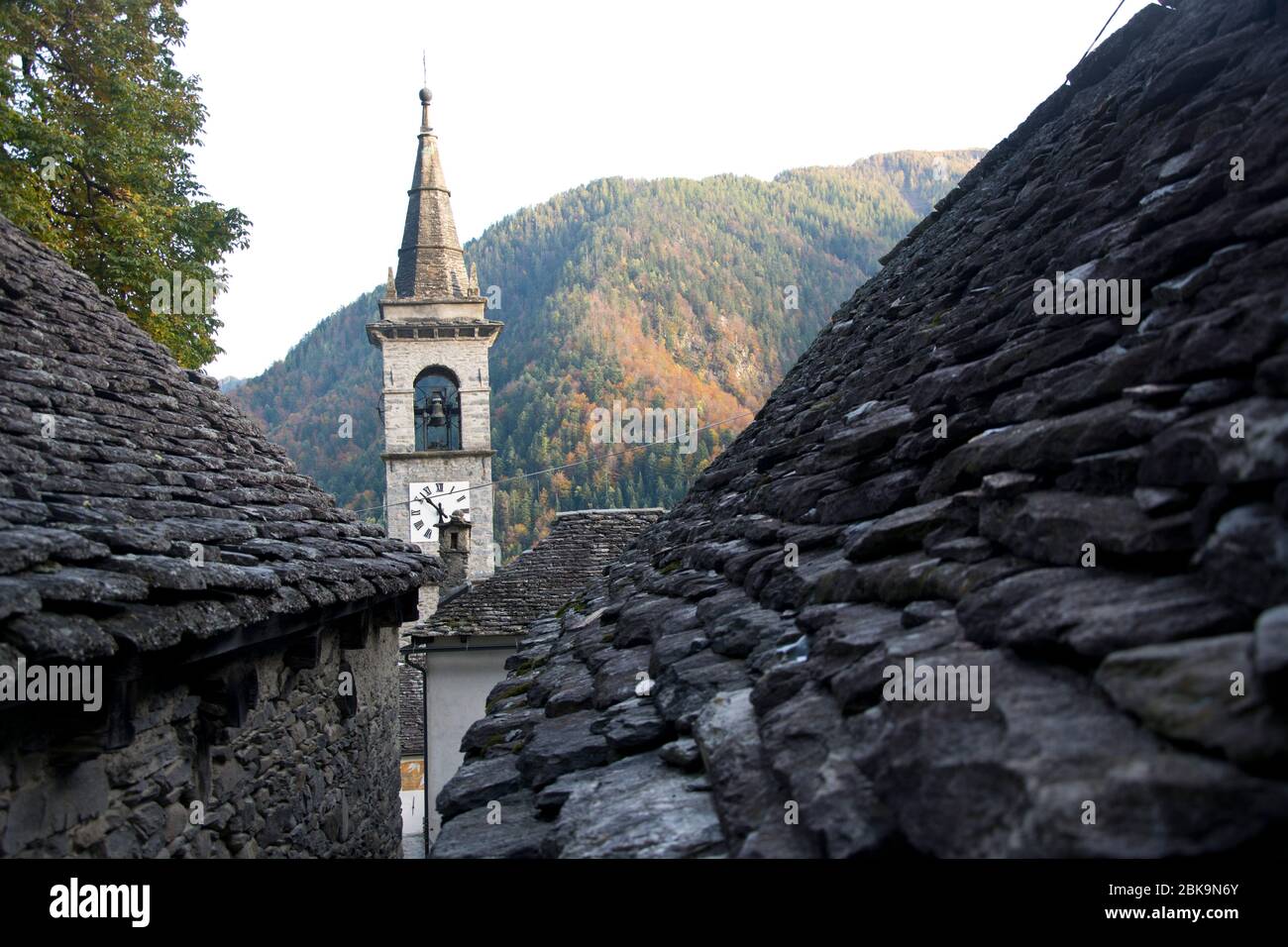 Blick über traditionelle Steindächer auf den Kirchturm von Spruga im Valle Onsernone im Tessin Stock Photo