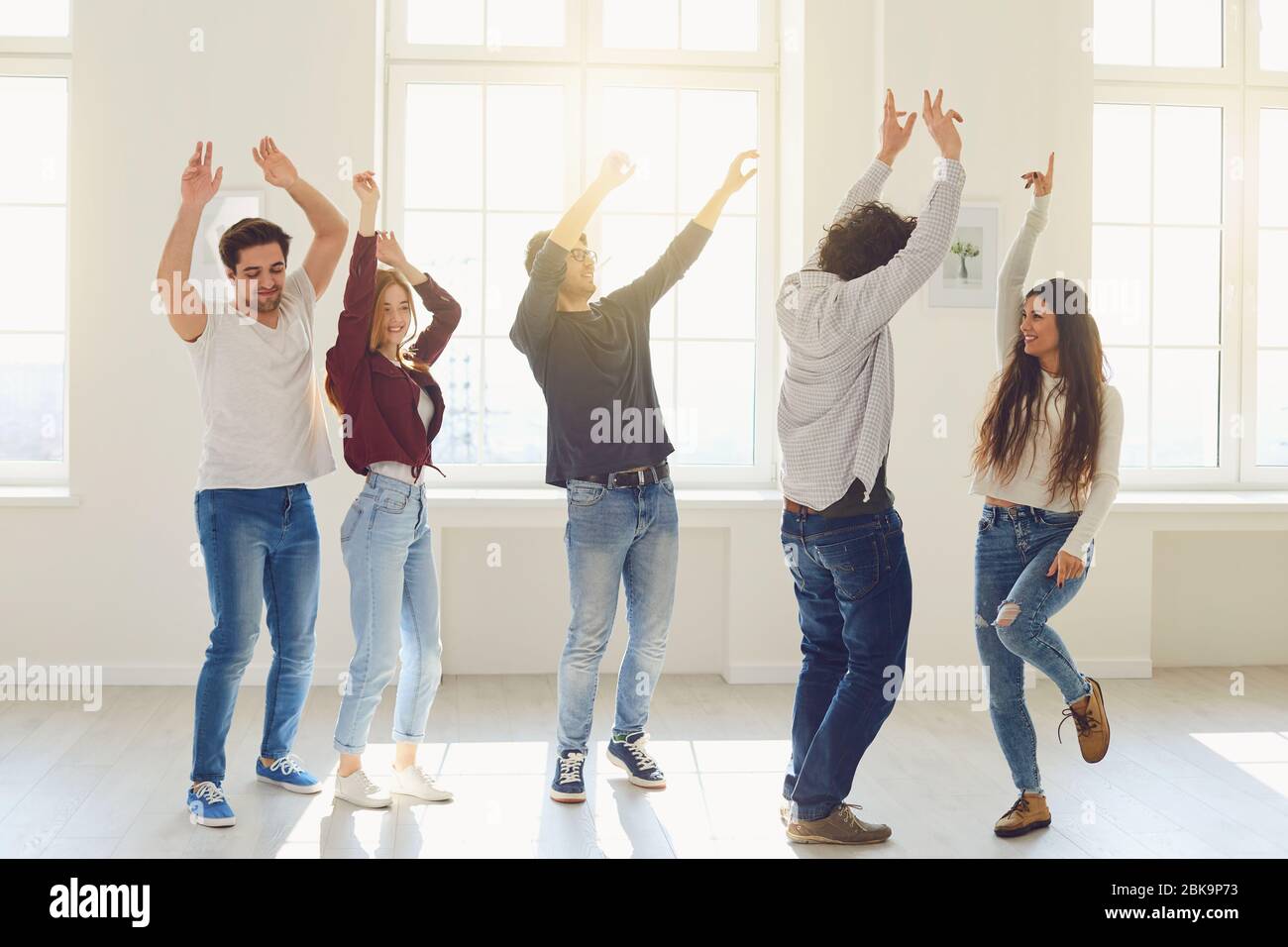 A group of friends are dancing fun in a room in a house. Stock Photo