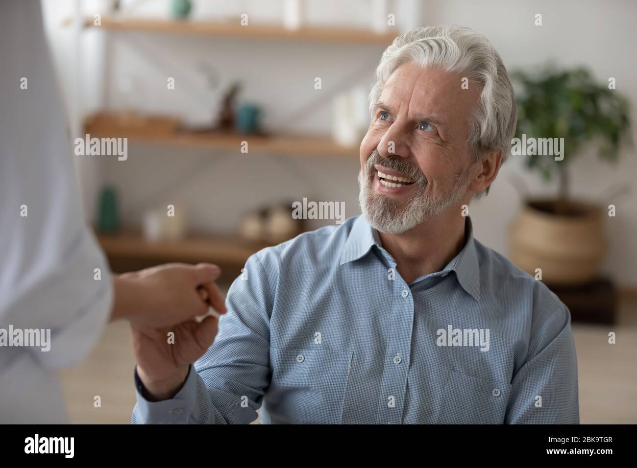 Happy senior man patient looking at doctor giving helping hand Stock Photo