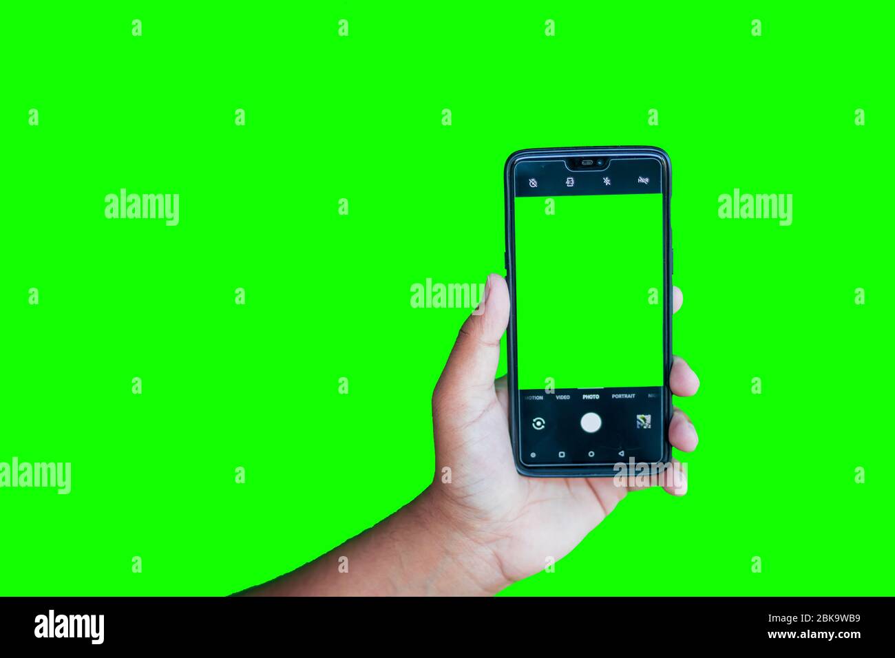 Man holding phone with camera interface against the green screen background Stock Photo