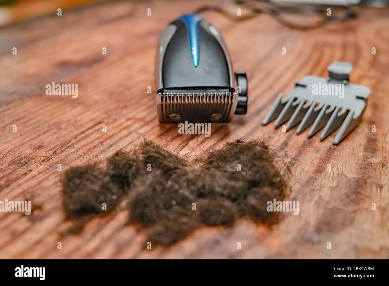 2 Front On View Of A Set Of Electric Hair Clippers And Shaved Hair On A Wooden Floor In A Hairdressing Salon With Intentional Selective Focus And Shal Stock Photo Alamy