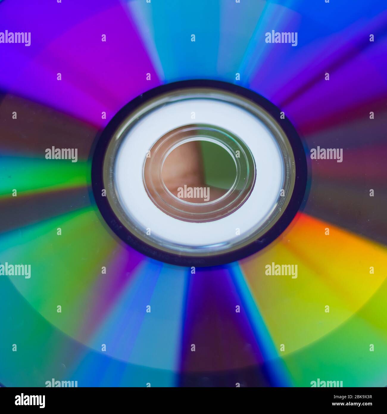 Compact Disc. Holding a CD in hands. The back side of the CD reflects colorful lights. Rainbow colors. Stock Photo