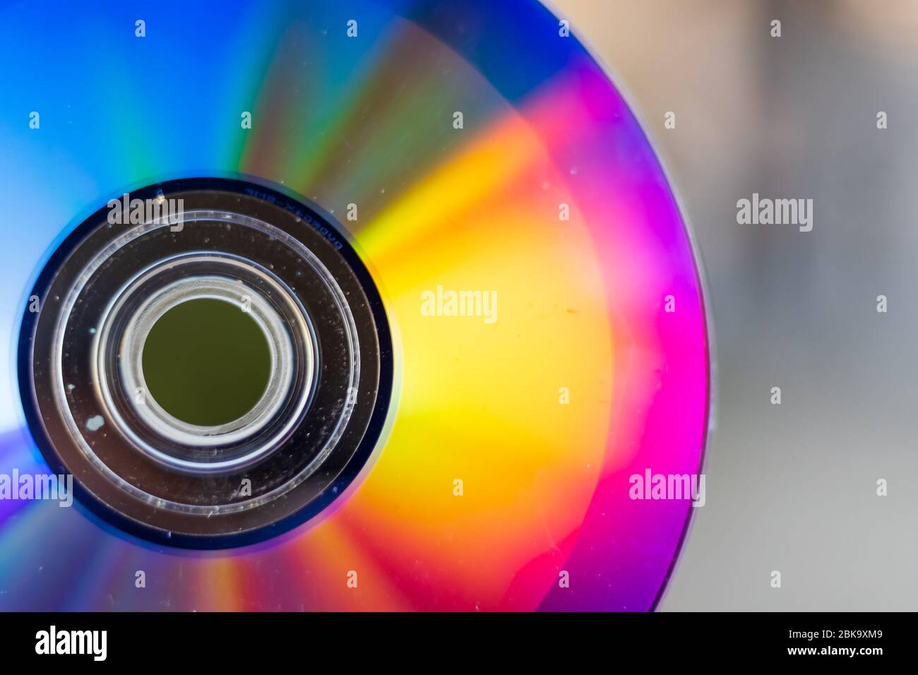 Compact Disc. Holding a CD in hands. The back side of the CD reflects colorful lights. Rainbow colors. Stock Photo