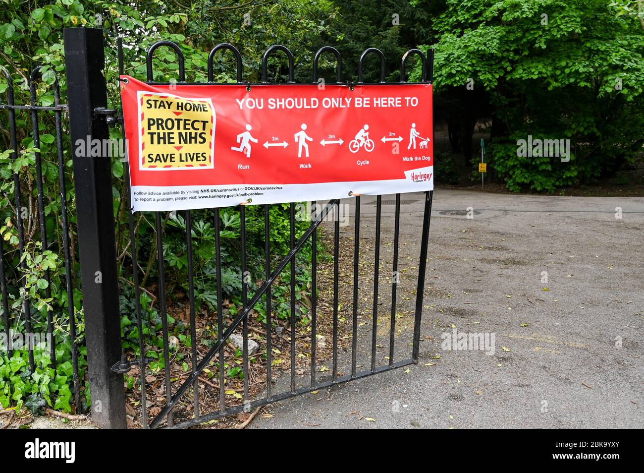 A banner on a park gate (Haringey, London) with 'stay home, protect the NHS' and 'You should only be here to run, walk, cycle or walk the dog'. Stock Photo