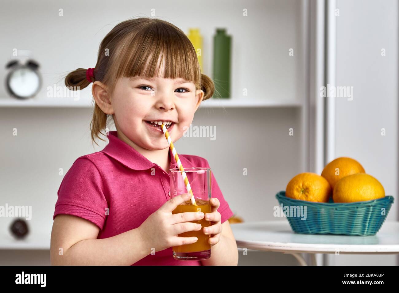 Cute little girl drinks orange juice at home Stock Photo - Alamy