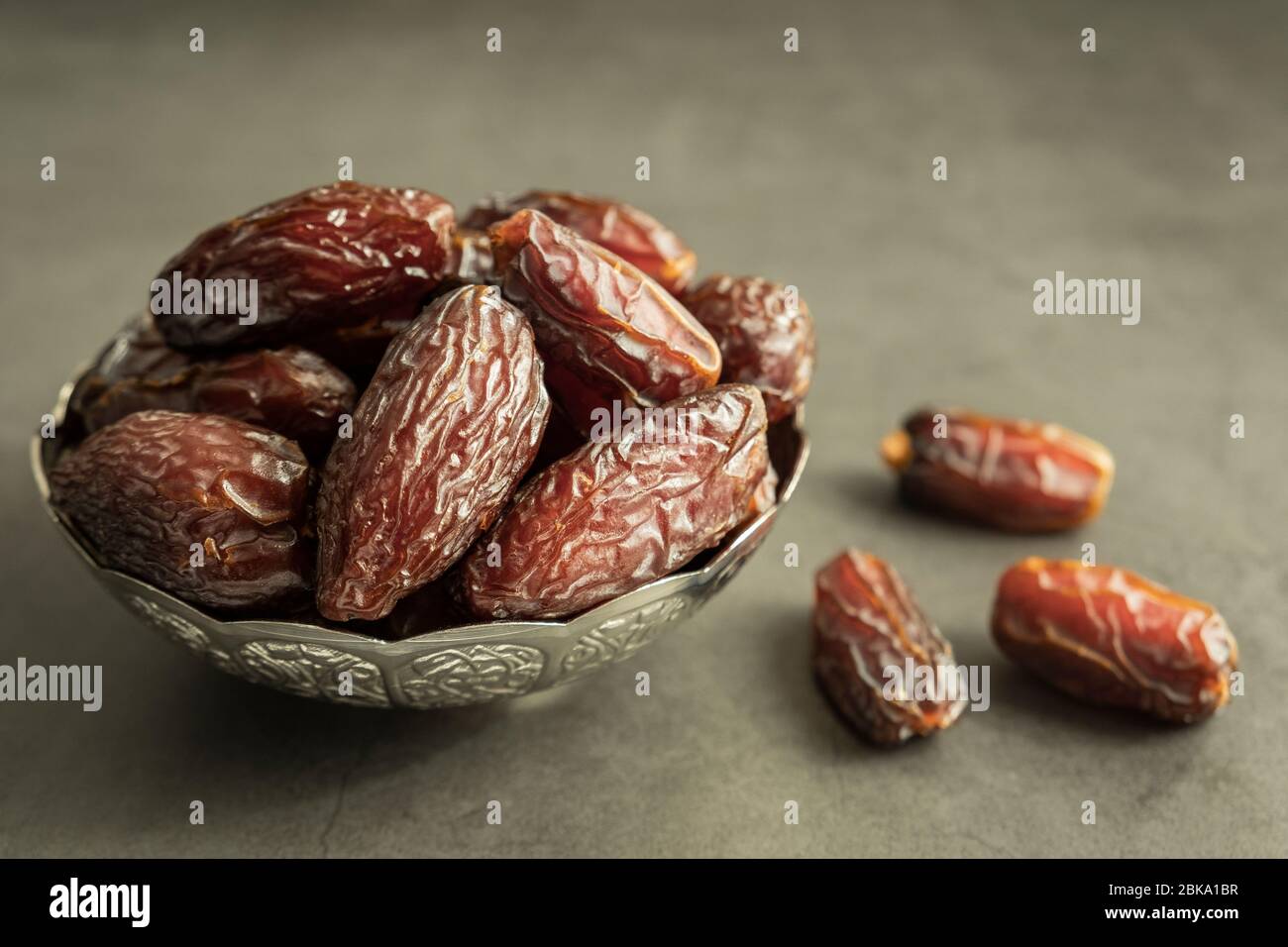 Raw date fruit ready to eat in silver bowl on concrete background. Traditional, delicious and healthy ramadan food. Stock Photo