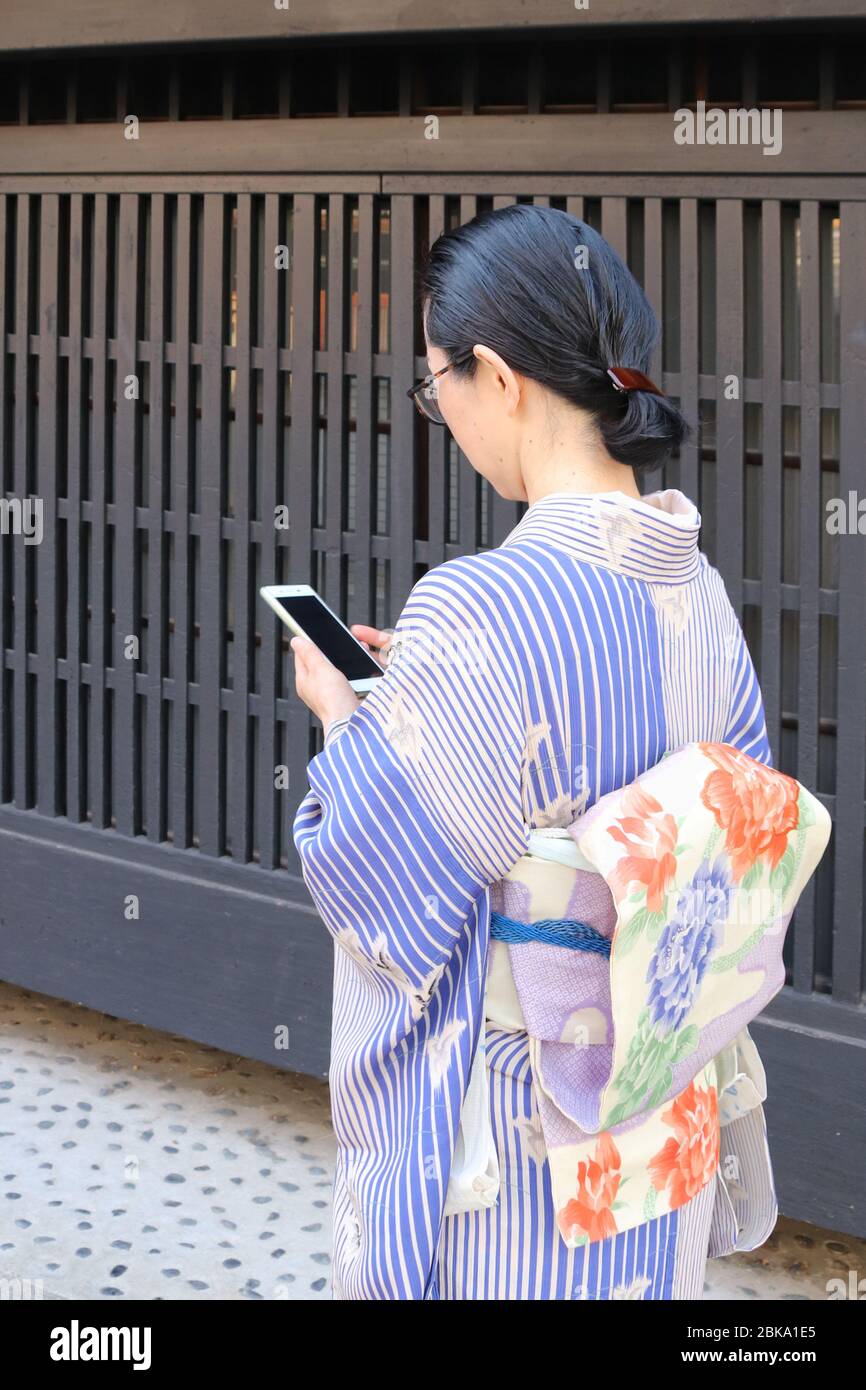Japanese woman in kimono checking her smartphone while walking Stock Photo