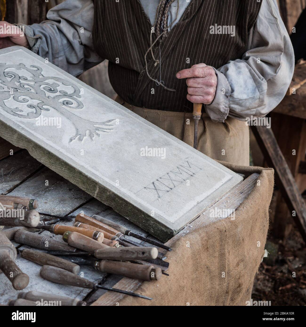 Vicenza, Italy - December 29, 2019: Stonemason carves and shapes the stone with a wooden hammer and chisel. Stock Photo