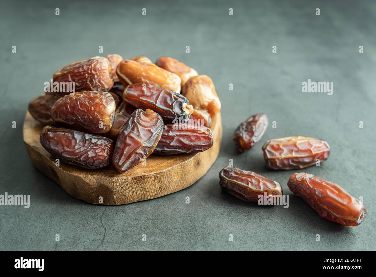 Raw date fruit ready to eat in wooden platter on concrete background. Traditional, delicious and healthy ramadan food. Stock Photo