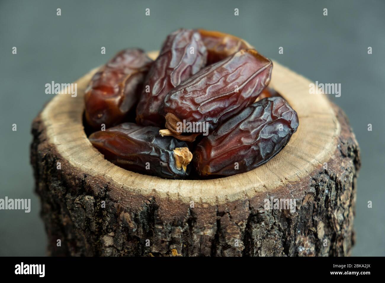 Raw date fruit ready to eat in wooden bowl on concrete background. Traditional, delicious and healthy ramadan food. Stock Photo