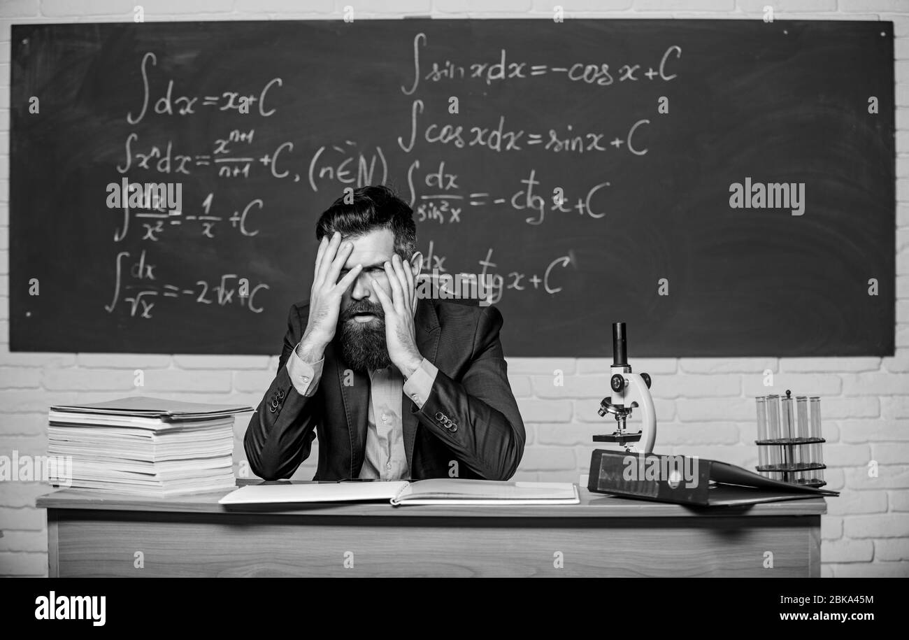Teaching dumb students. No hope for better. Tired and exhausted. Teacher mature man. Fed up. Difficult work. Emotional burnout. Teacher give up. Hate his job. Man desperate teacher in classroom. Stock Photo