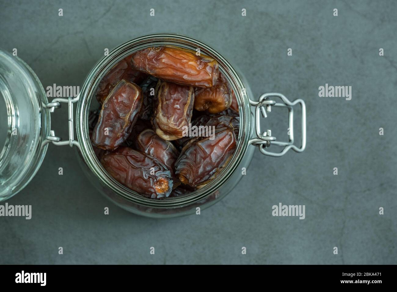 Raw date fruit ready to eat in glass jar on concrete background. Traditional, delicious and healthy ramadan food. Flat lay, top view. Stock Photo