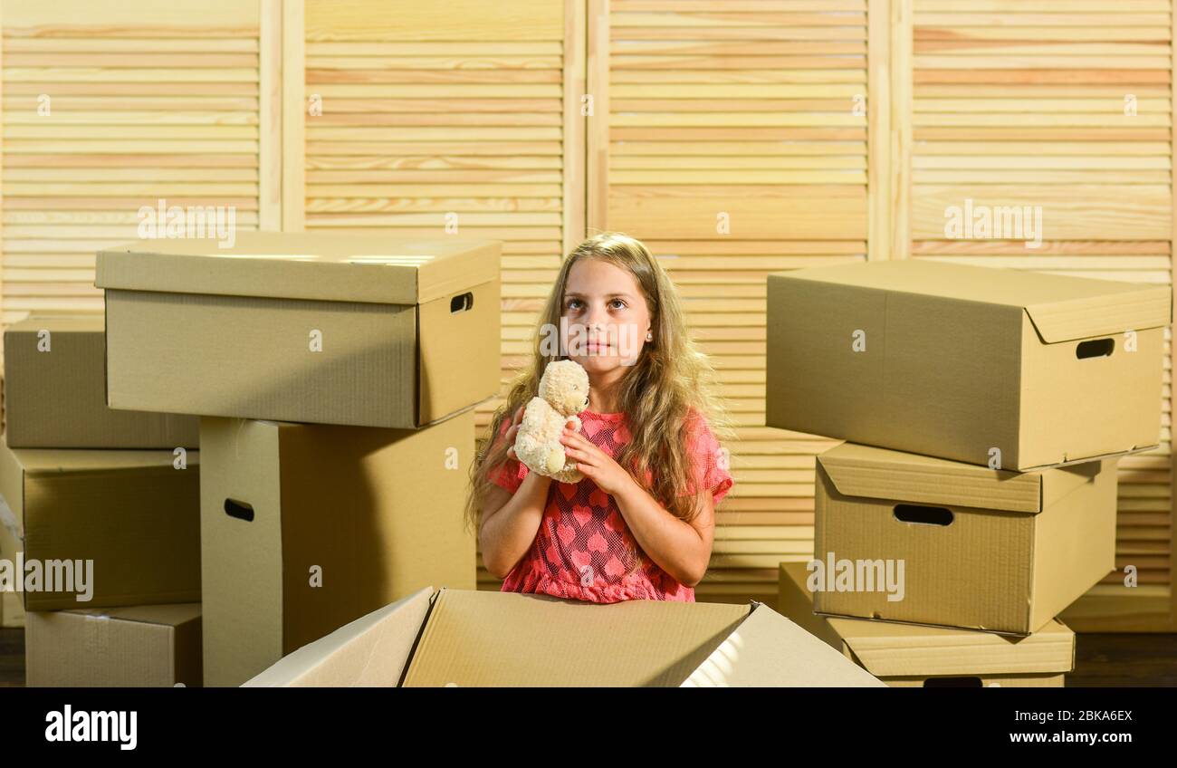 Packaging things. Only true friend. Girl child play with toy near boxes. Move out concept. Stressful situation. Divorce and separation. Family problem. Prepare for moving. Moving out. Moving routine. Stock Photo