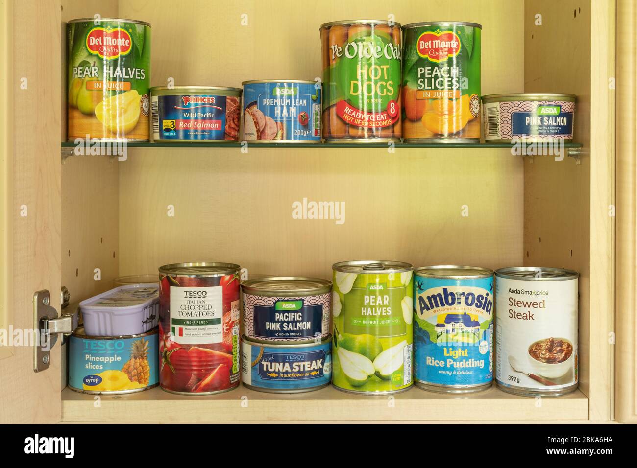 Tinned food (canned food) in a kitchen store cupboard. Tins, cans. Stock Photo