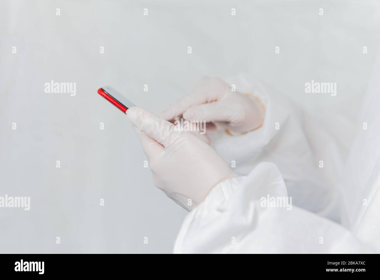 Nurse or doctor using technology phone to communicate and research information wearing protective biohazard suit and gloves during covid 19 pandemic Stock Photo