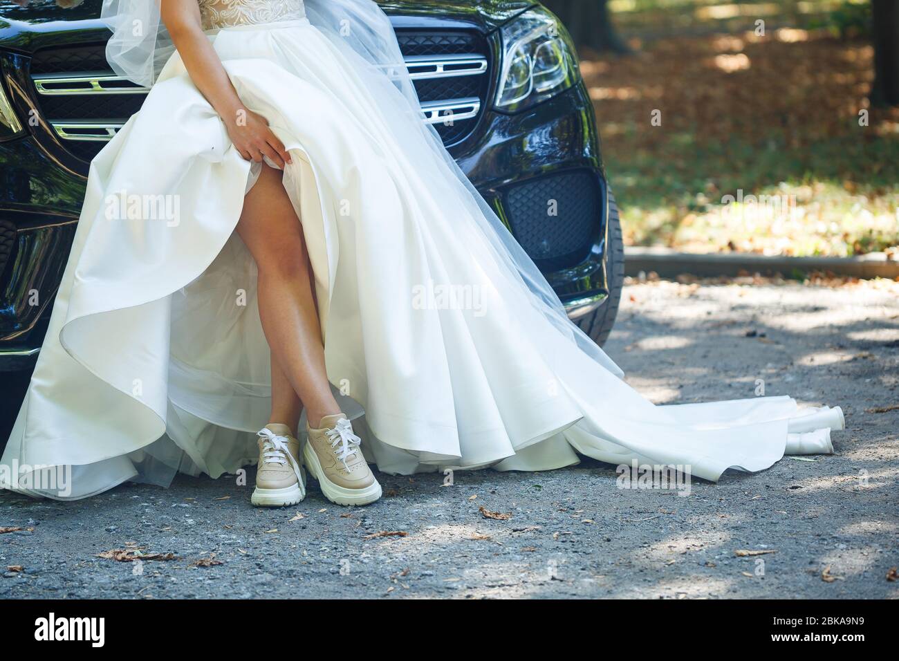 Bride in a white dress and sneakers on a wedding day Stock Photo - Alamy