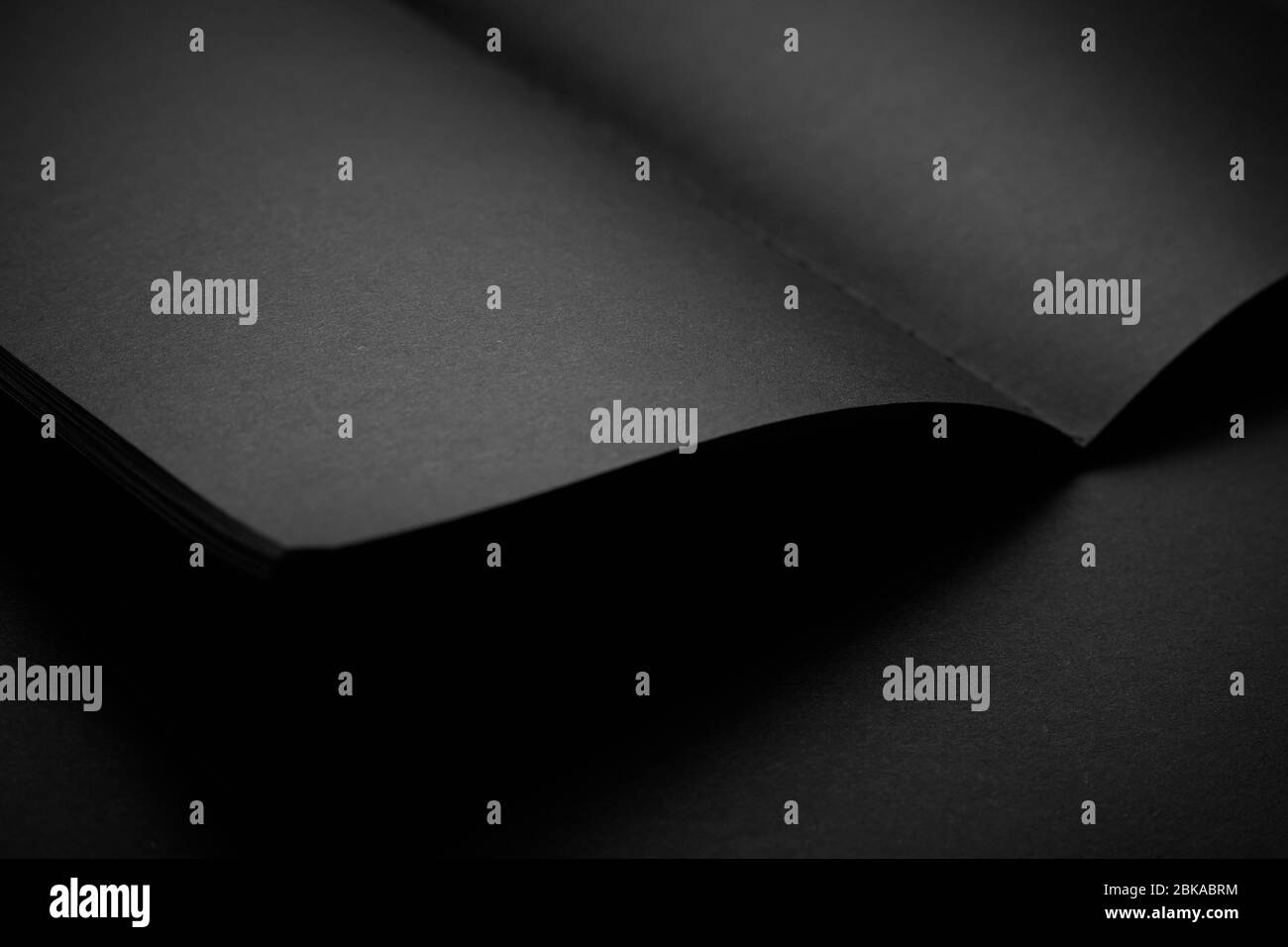 Blank black notebook on a black table, mockup photo. Blank black cover