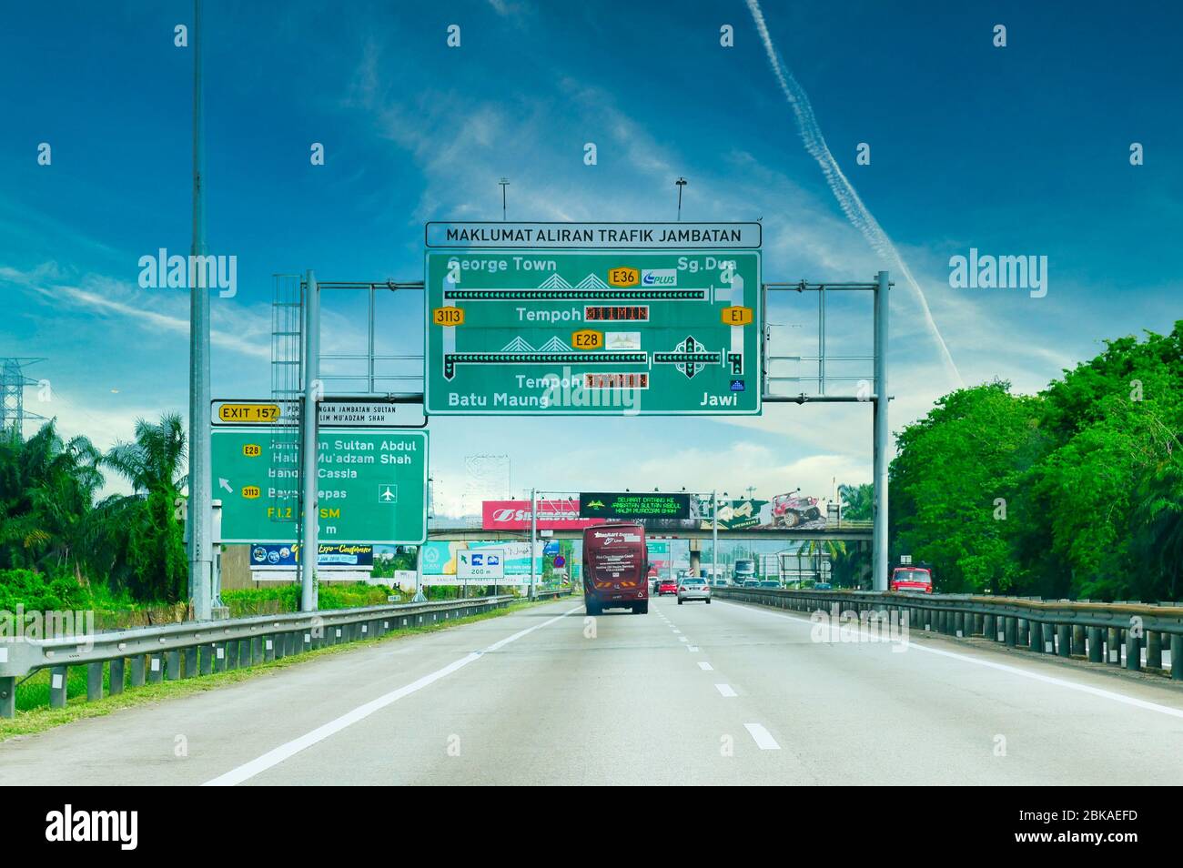 Northbound on the E1 toll highway at Simpang Ampat 500m before Exit 157 to E28 / Penang Bridge, showing road signs and traffic on a sunny day with blu Stock Photo