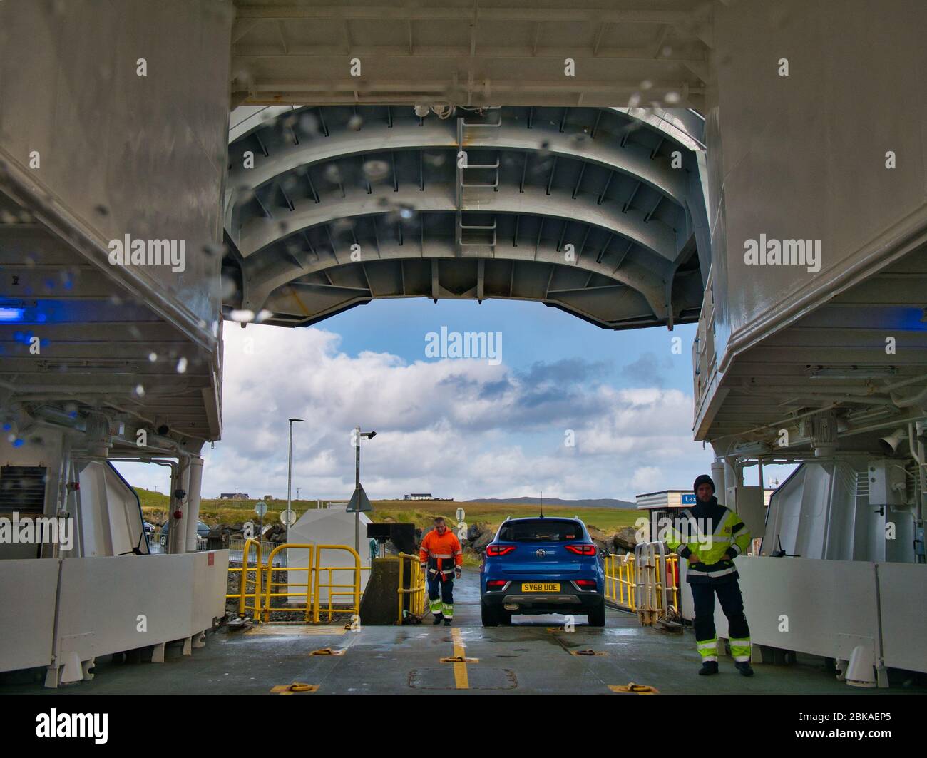 With the ship's bow door raised and raindrops visible on the windscreen, a vehicle prepares to disembark the car deck of a roll on/roll off car ferry Stock Photo