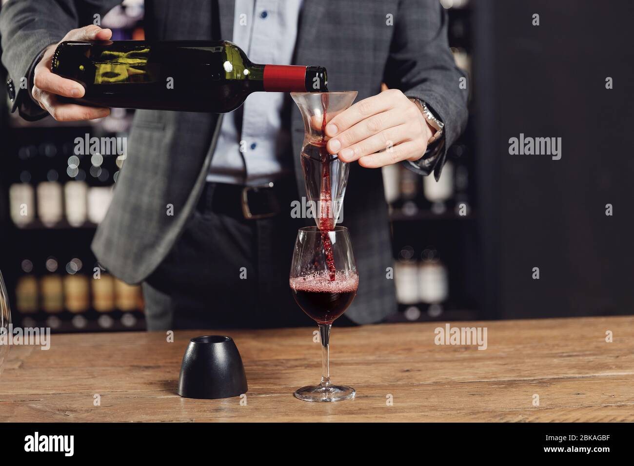 Sommelier pouring red wine into bottle decanter glass to make aeration