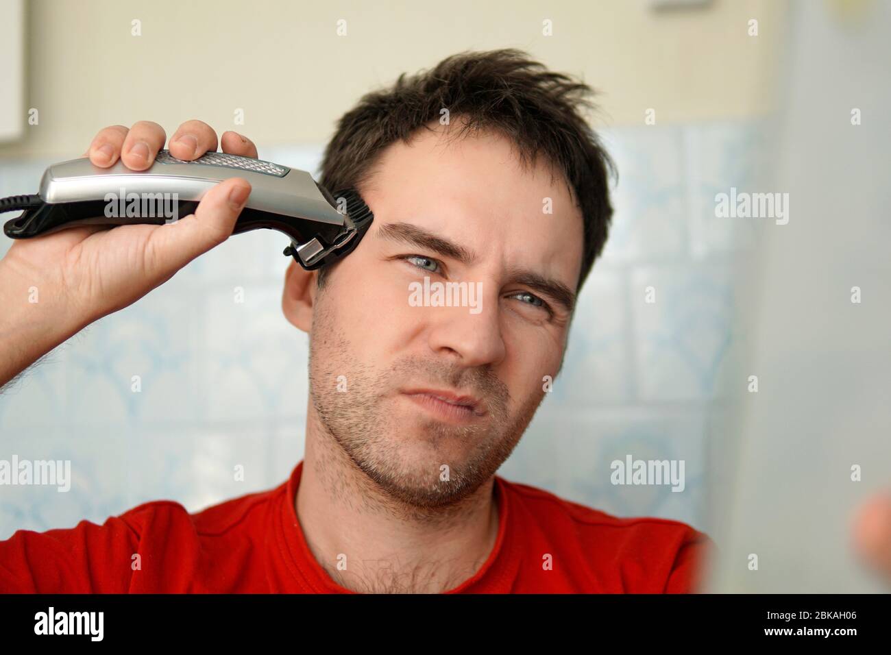A man cuts his hair on his head with an electric razor. Clean yourself