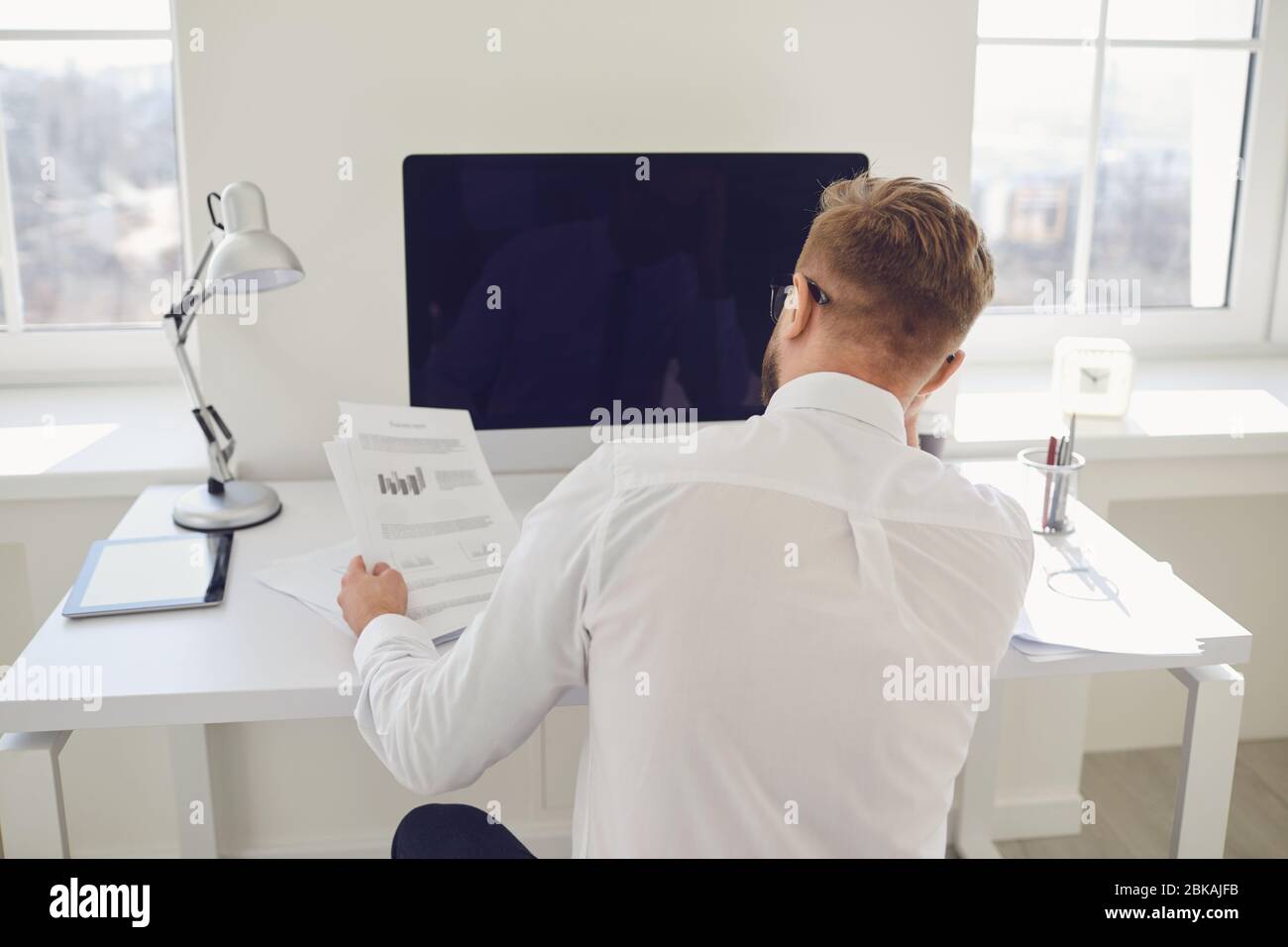 Businessman works at a table with a computer in the office. Back view ...