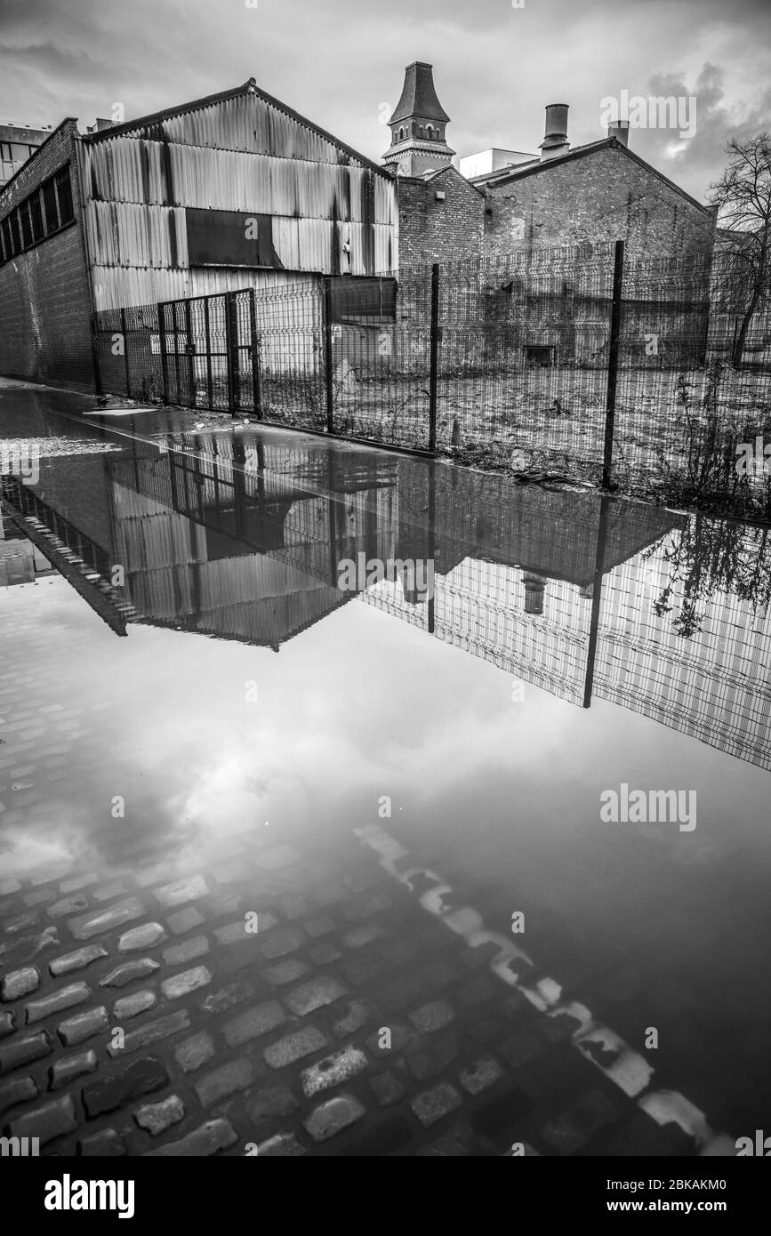 A view of disused industrial units in the post-industrial district of Ancoats, reflected in a large puddle. Stock Photo