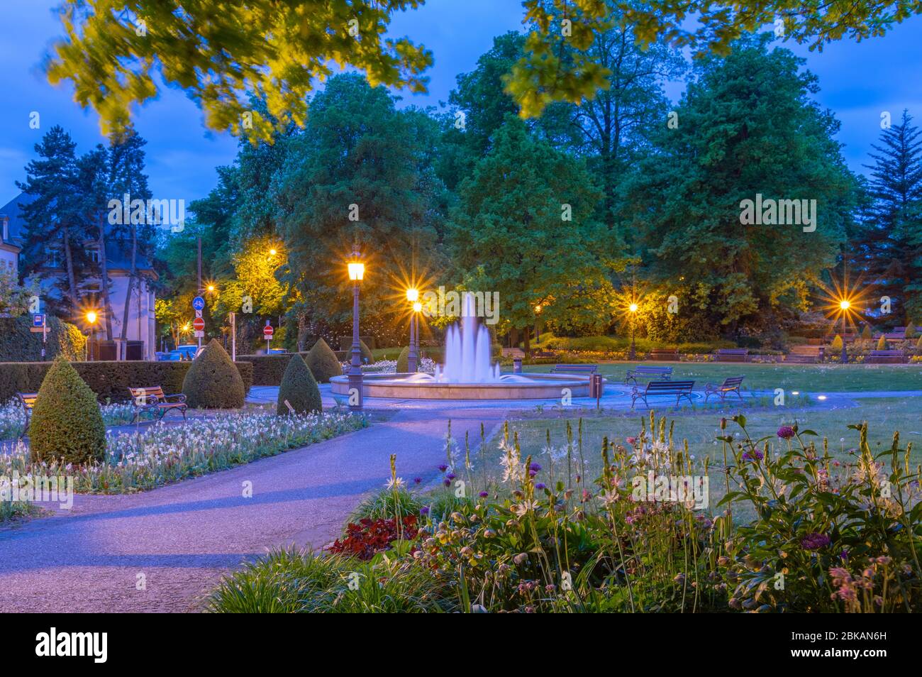 Central city park in Luxembourg City at night when the darkness is falling, shadows are long and streetlamps are already lit Stock Photo