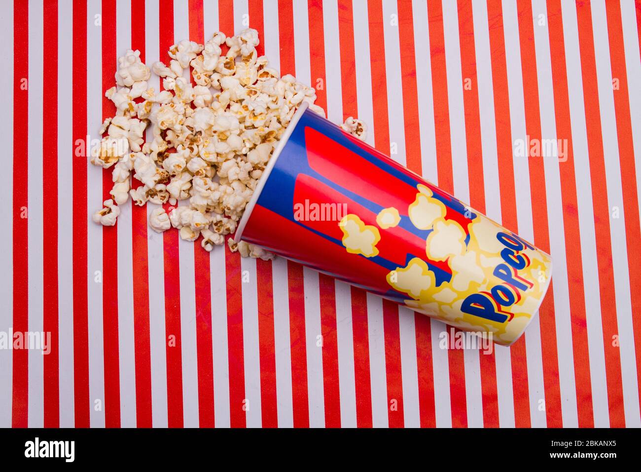 Close up popcorn was scattered from box on striped background. Stock Photo