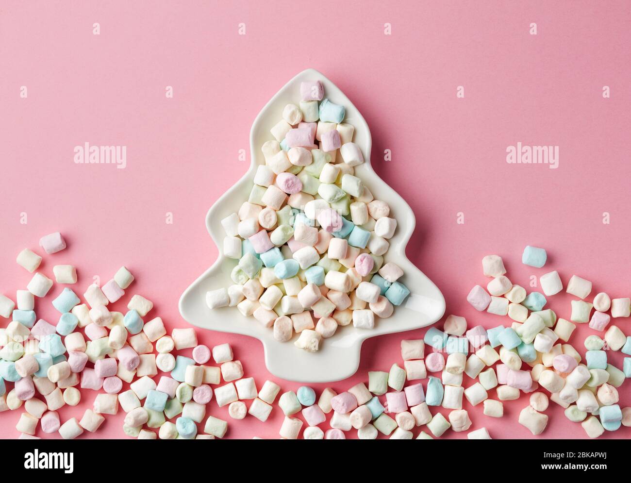 mini marshmallows on fir shape plate, christmas snack on pink background, top view Stock Photo