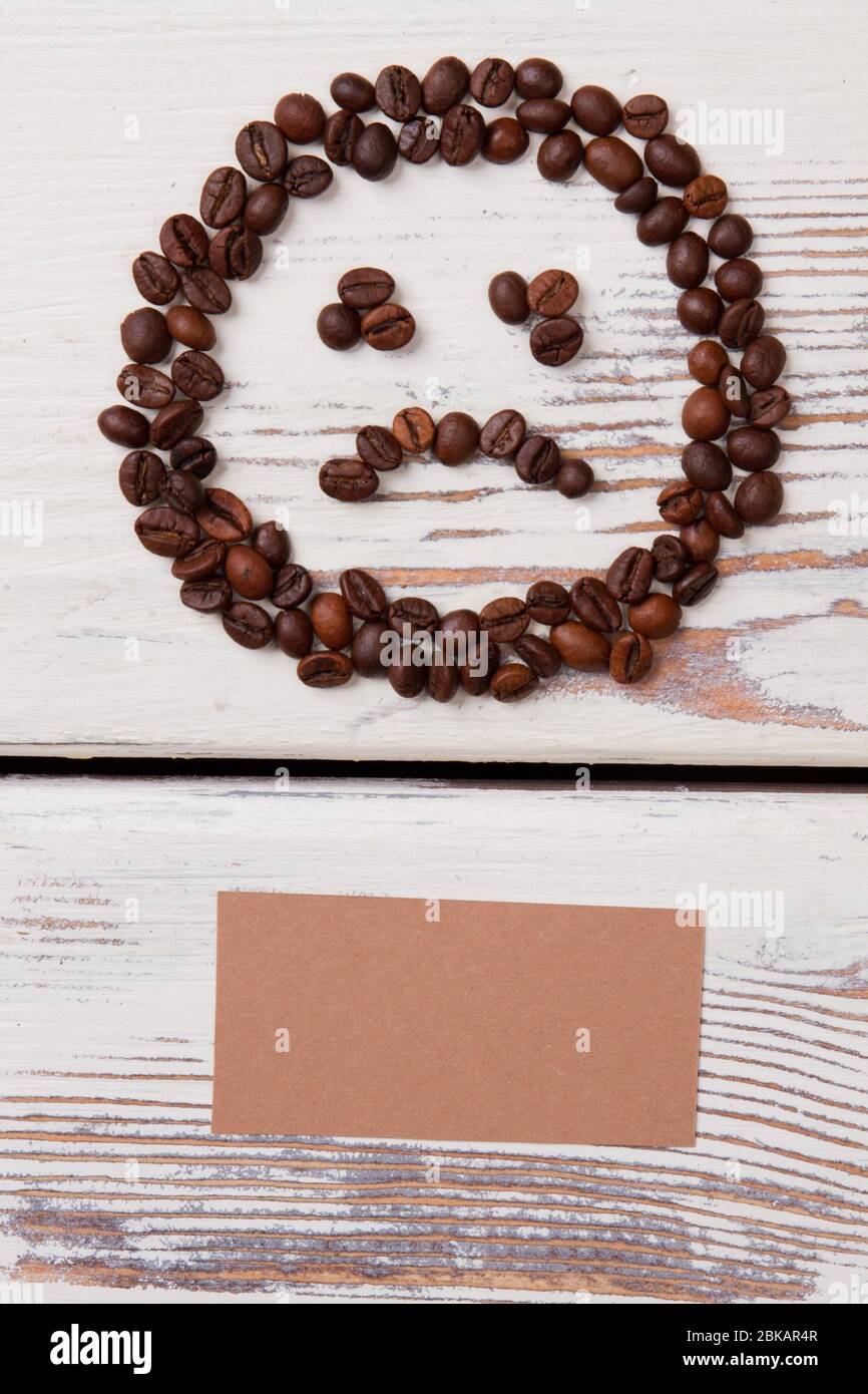 Sad smiley face made of coffee beans and blank beige paper. Stock Photo