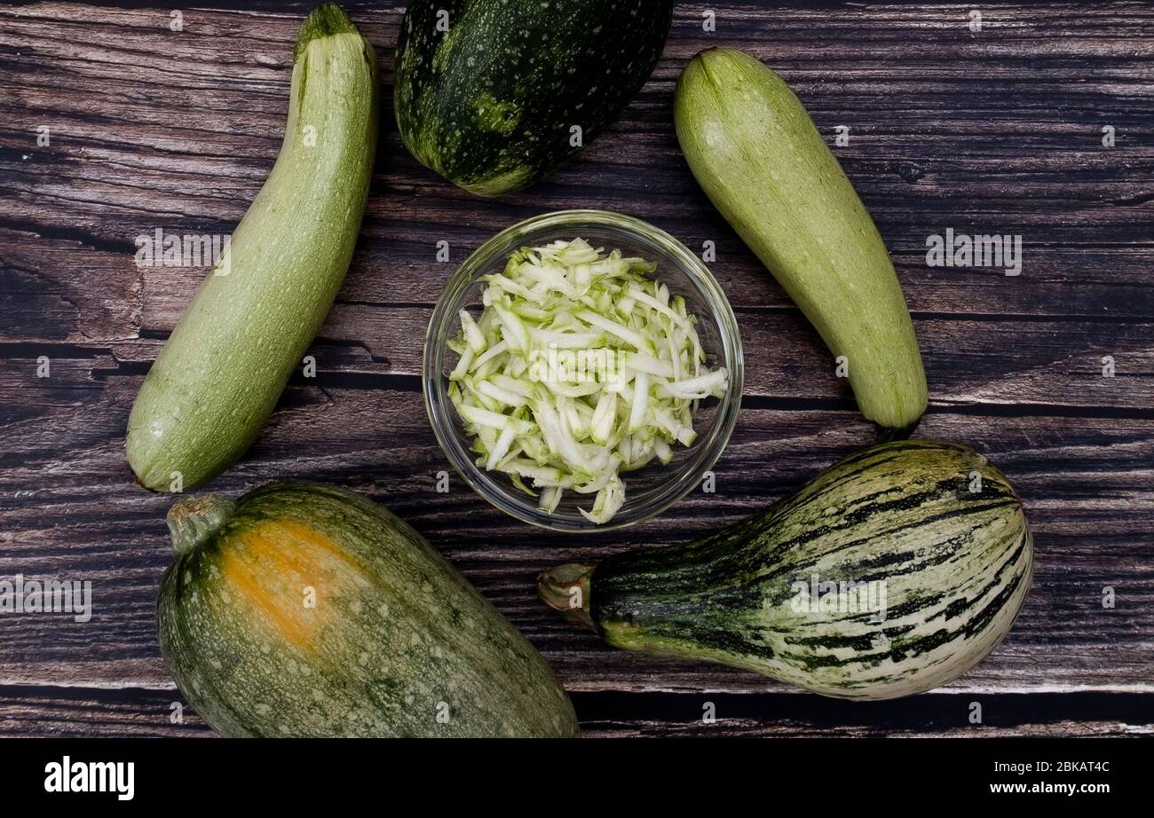 Grated zucchini and different type of zucchinis on wood background. Top