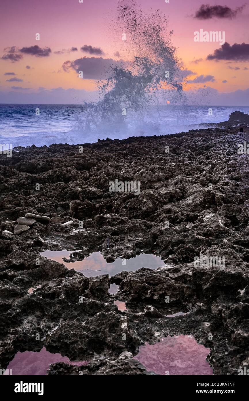 Large waves crashing against rocks at sunset, Grand Cayman Blowholes Stock Photo