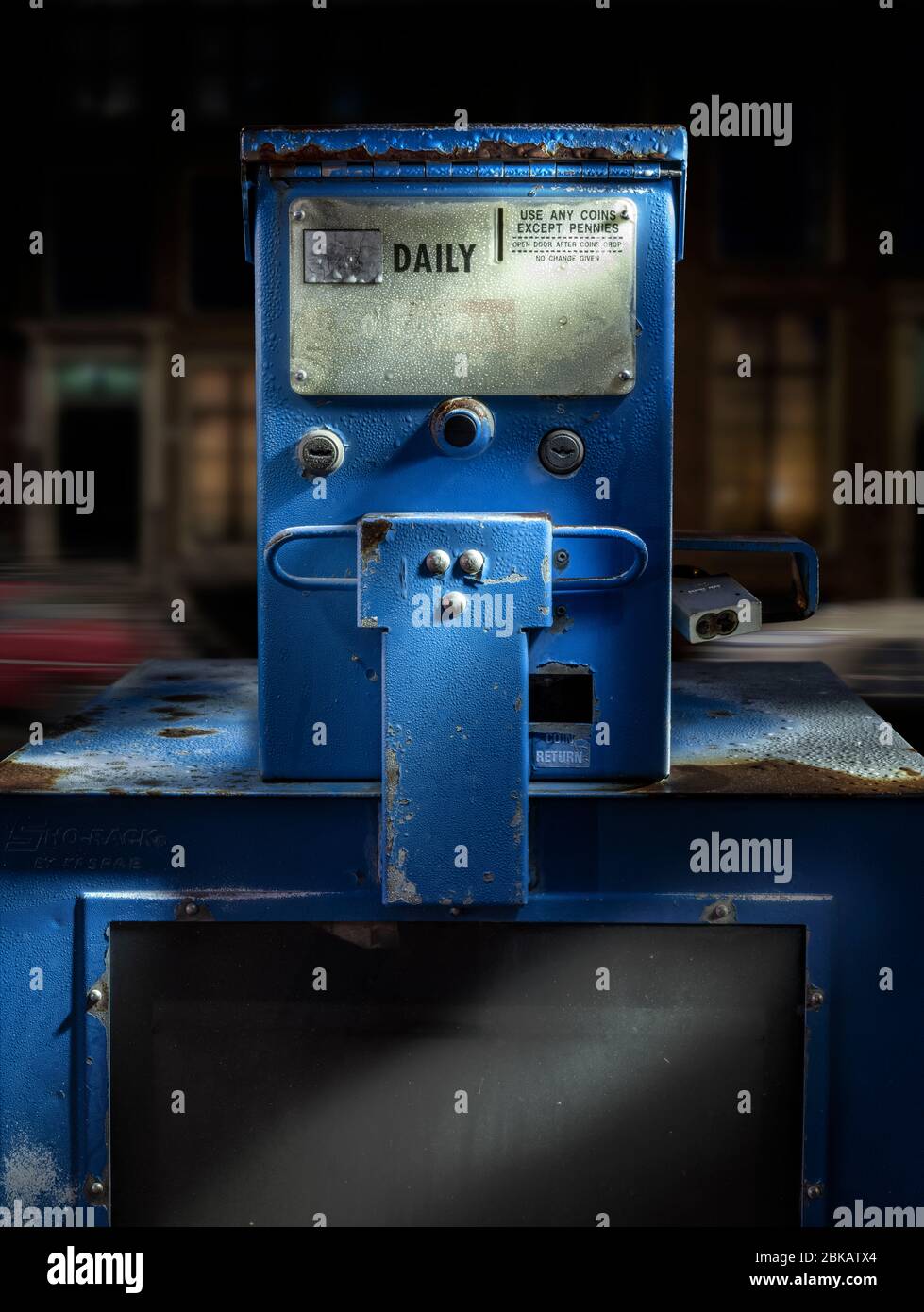 Old newspaper vending machine on city street at night Stock Photo