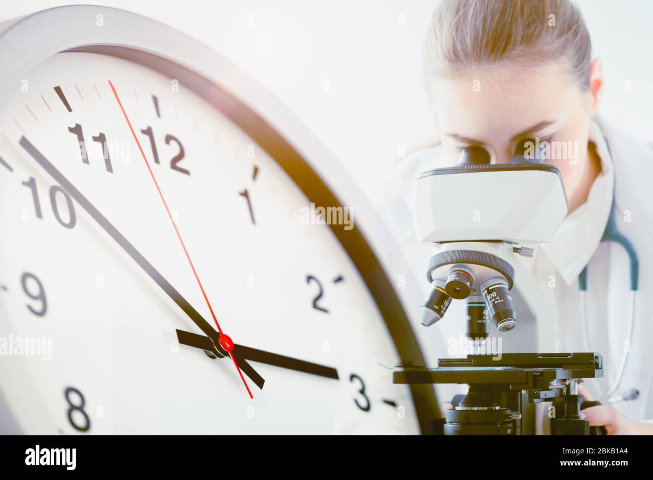 Doctor working at laboratory with Times clock face for Scientists researching vaccines to compete with time to fight Covid-19 concept Stock Photo