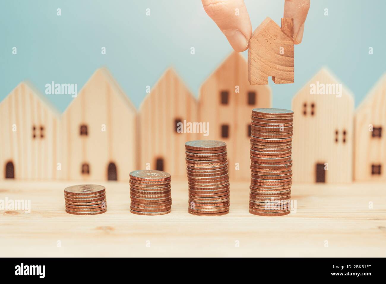 Coin stack with wooden home model for saving money to buy a new home concept. Stock Photo