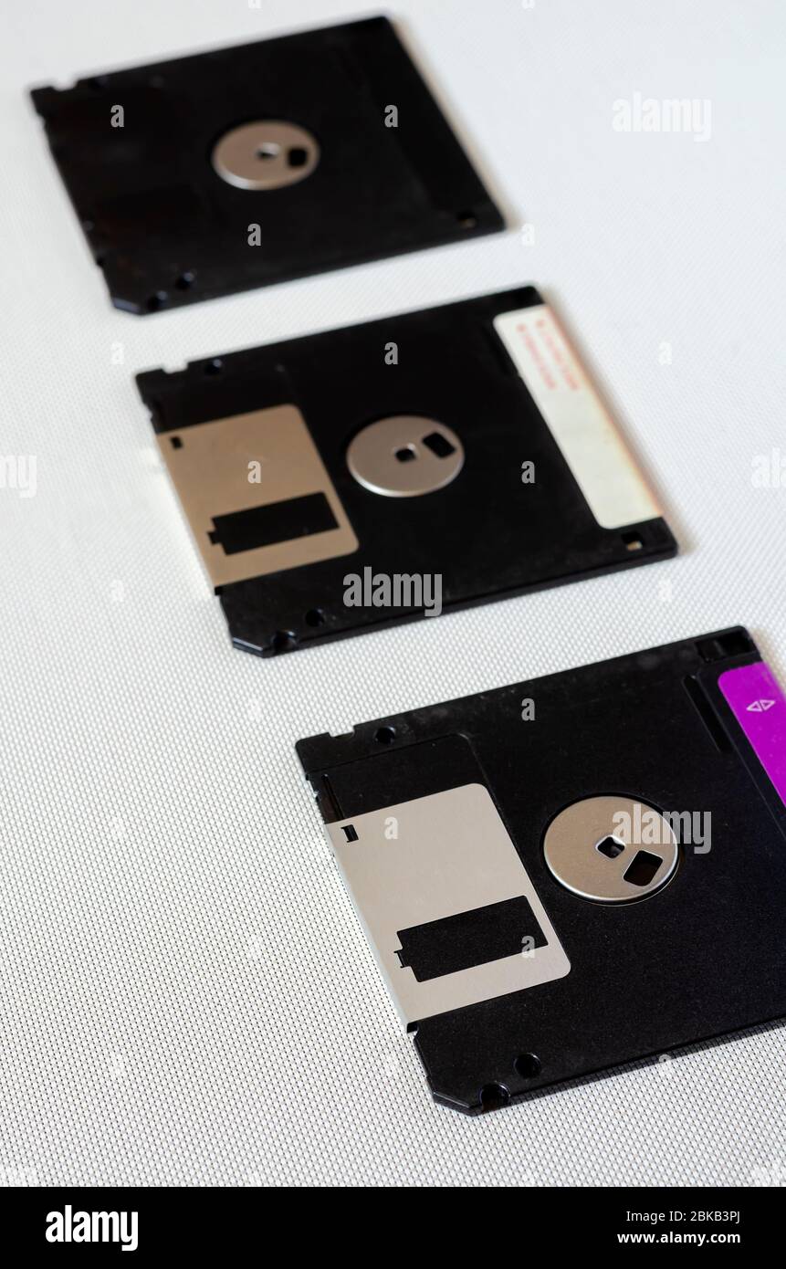 Three floppy disks on a white textured background. Floppy disks with a capacity of 1.44 MB. 3.5 inch magnetic floppy disks. Obsolete digital data stor Stock Photo