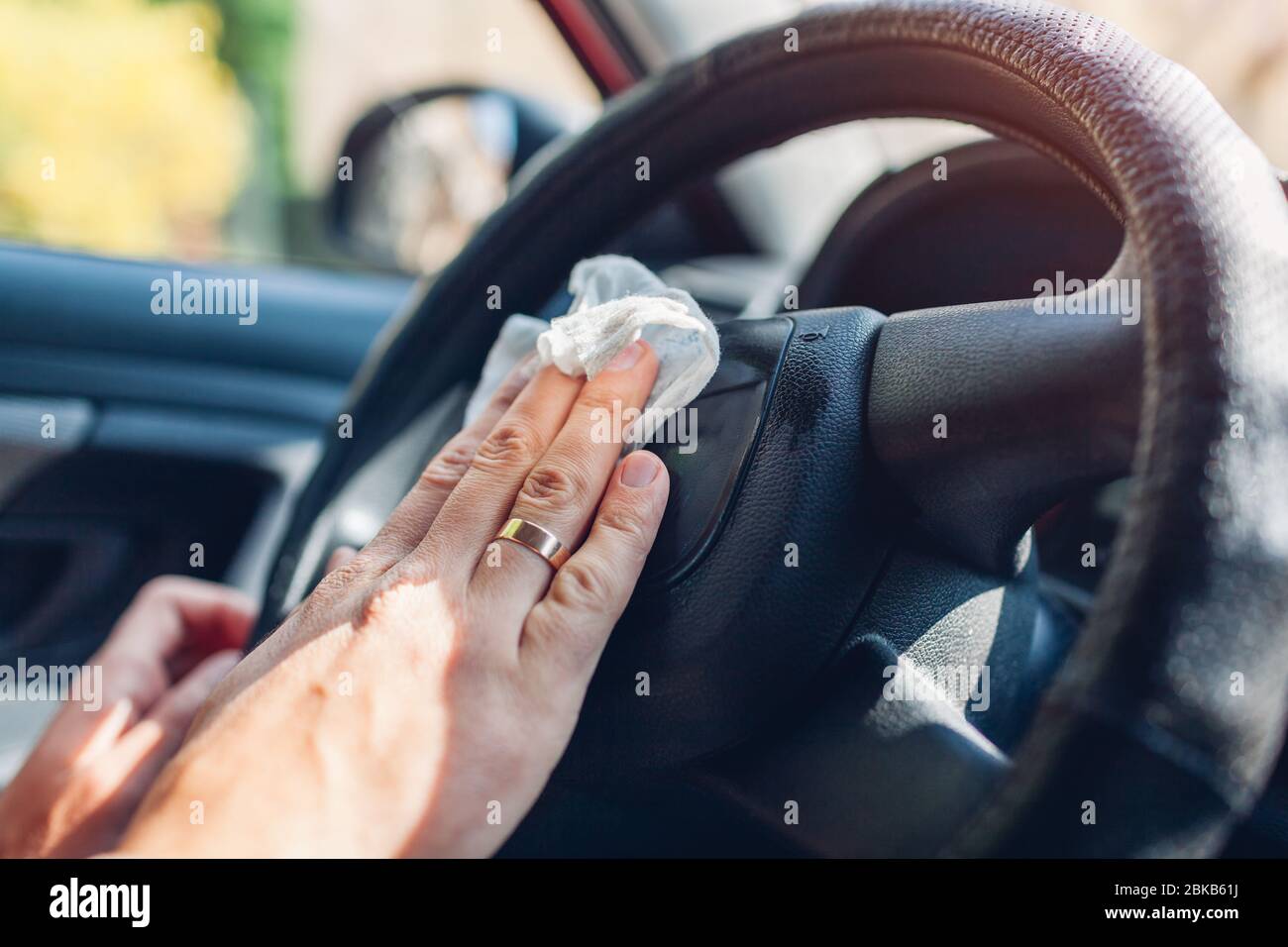 Coronavirus car disinfection. Man cleans interior wheel with wet