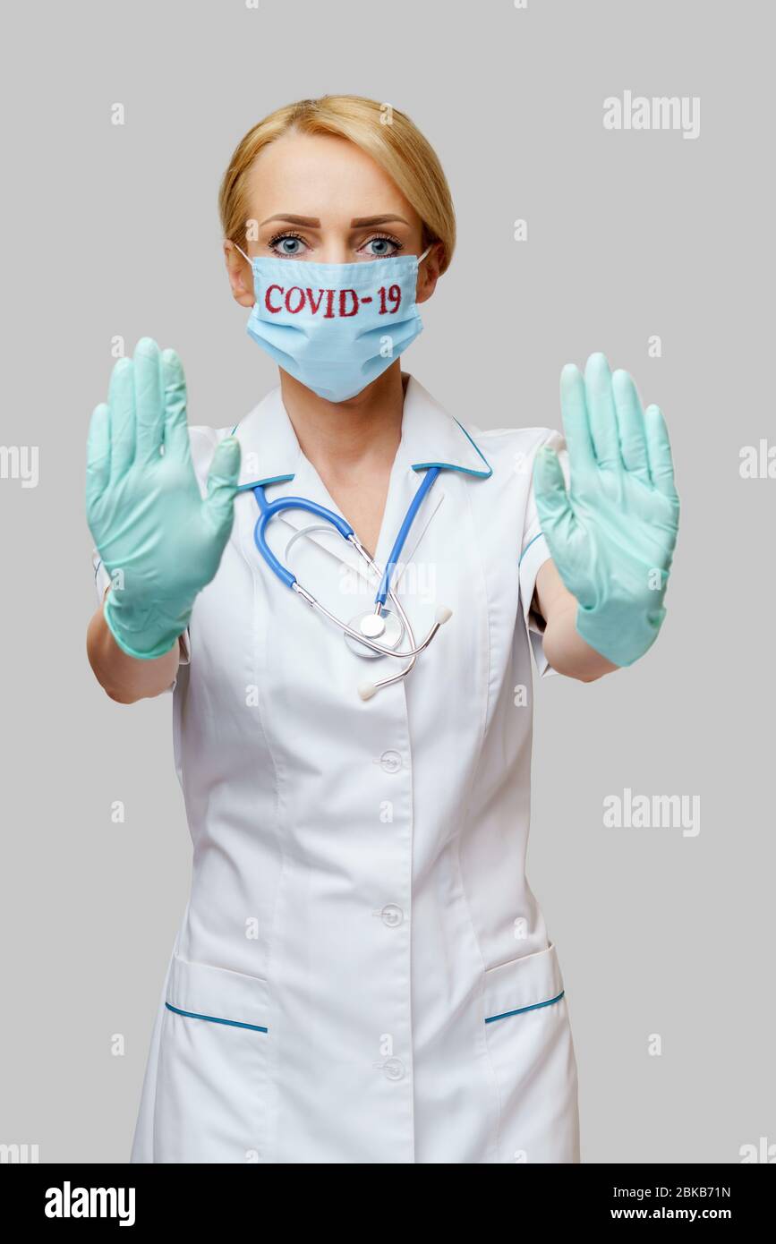 female doctor with stethoscope wearing protective mask and latex gloves ...