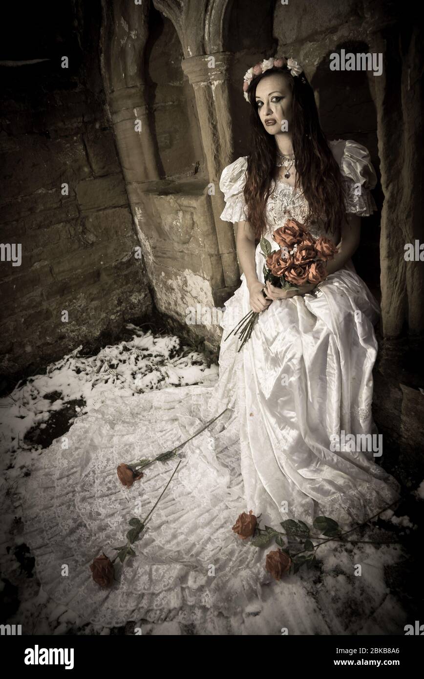 The tragic Vampire Bride in the remains of a ruined stone building, on a snowy winters day. Stock Photo