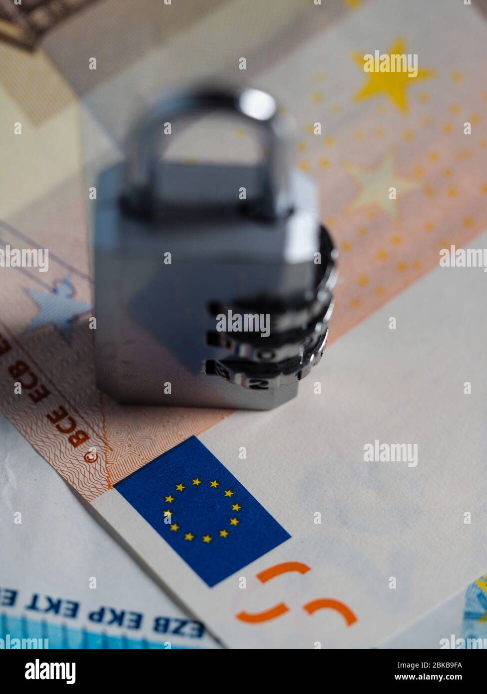 Money printing and emission locked in the eurozone. A password protected lock in the hands of the european union blocking euro cash currency. Stock Photo