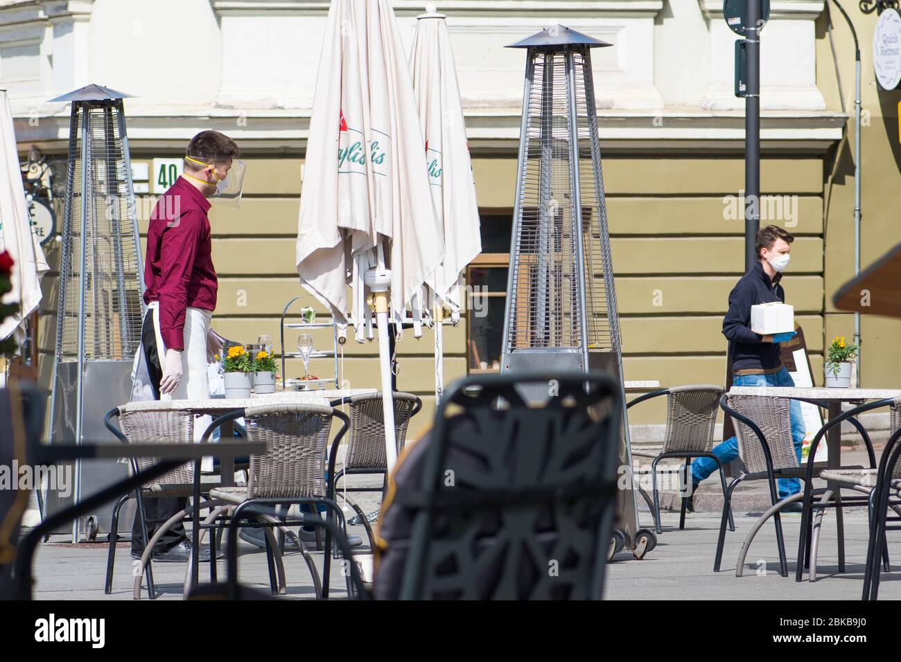 Waiter with a mask disinfects the table of an outdoor bar, café or restaurant, reopen after quarantine restrictions Stock Photo