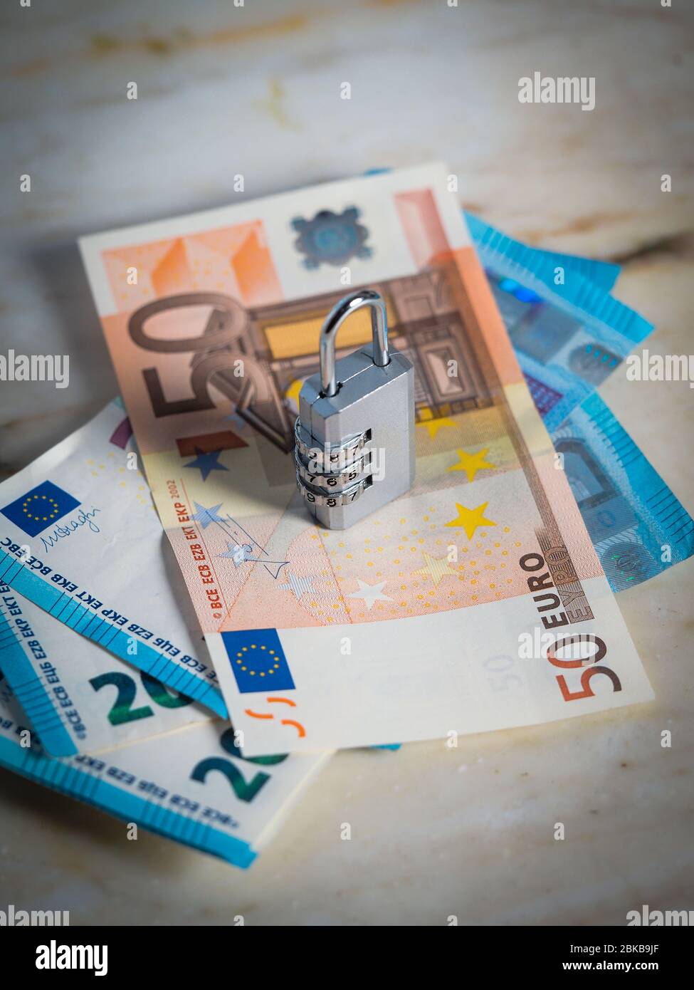 Money printing and emission locked in the eurozone. A password protected lock in the hands of the european union blocking euro cash currency. Stock Photo