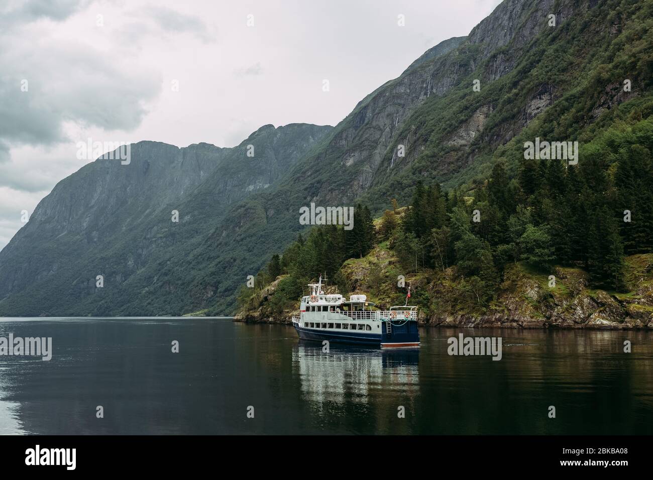 tourist ship on a mountain river against the background of the Norwegian mountains and the sky covered with shells Stock Photo
