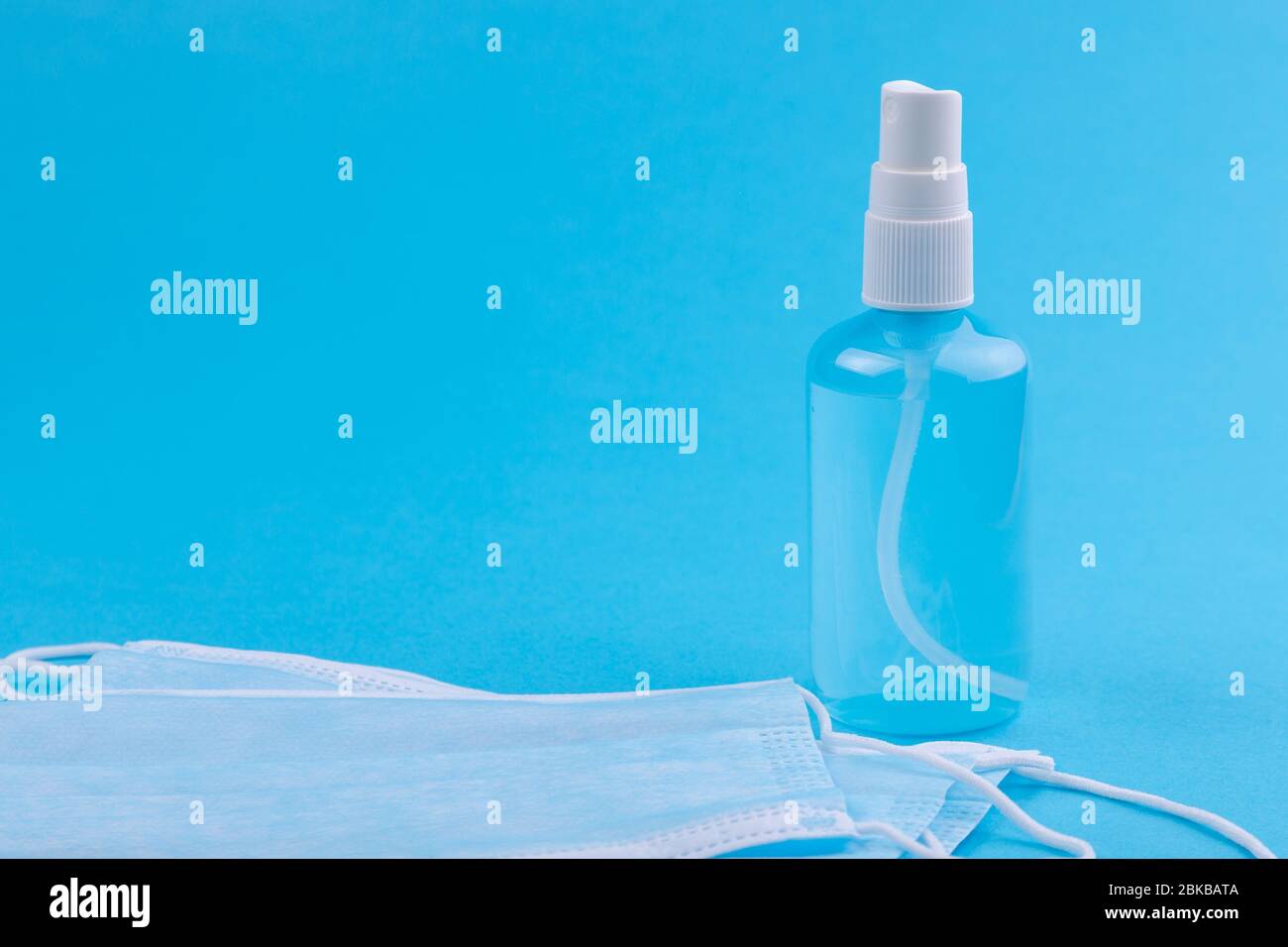 Medical mask and antiseptic spray isolated on blue Stock Photo